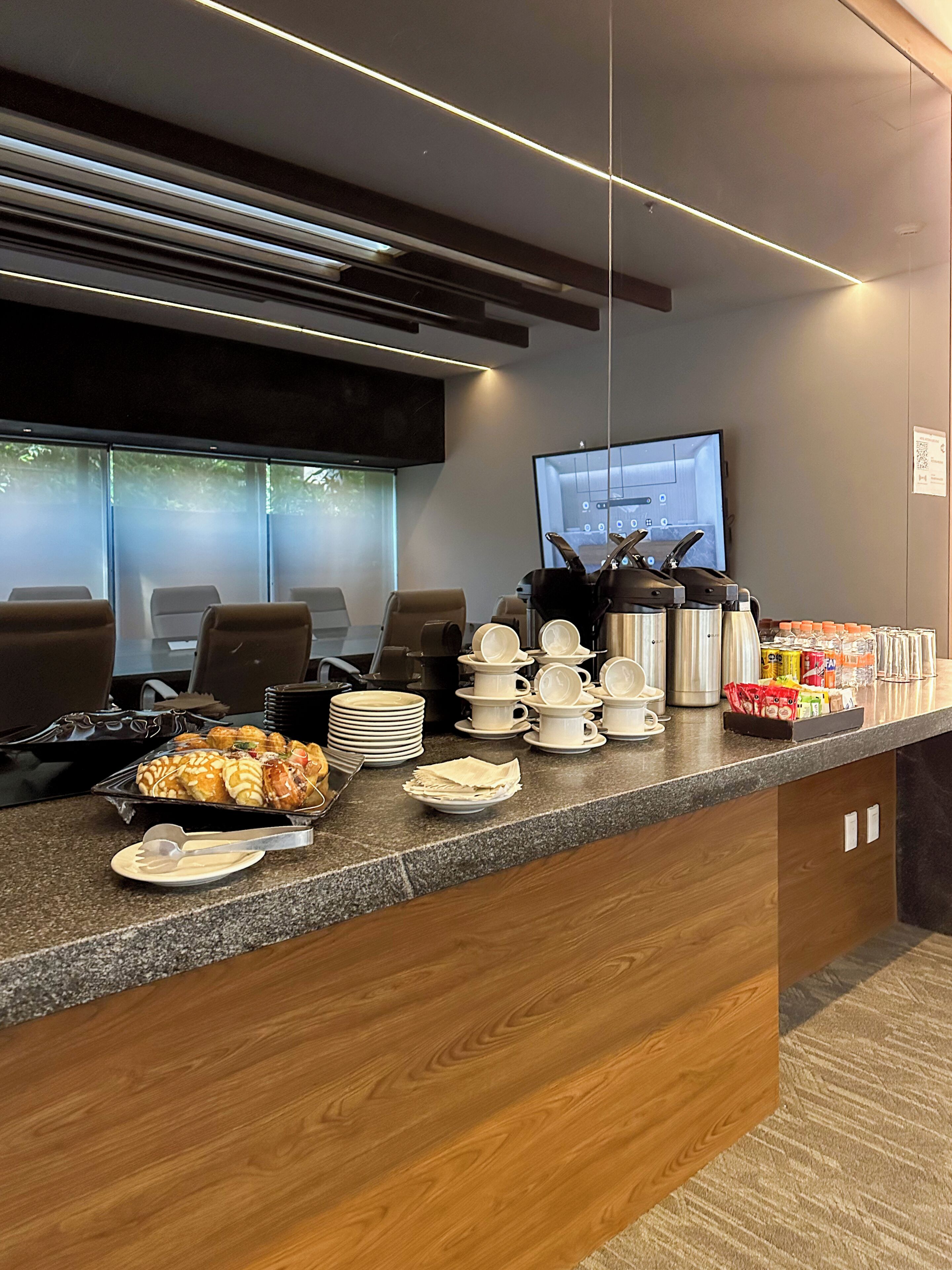 Un área de recepción con un mostrador que exhibe alimentos, un televisor y asientos.