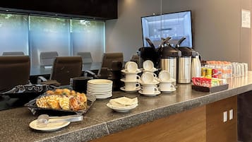 Un área de recepción con un mostrador que exhibe alimentos, un televisor y asientos.