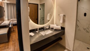 Une salle de bain moderne avec un grand miroir, deux lavabos et un espace douche.