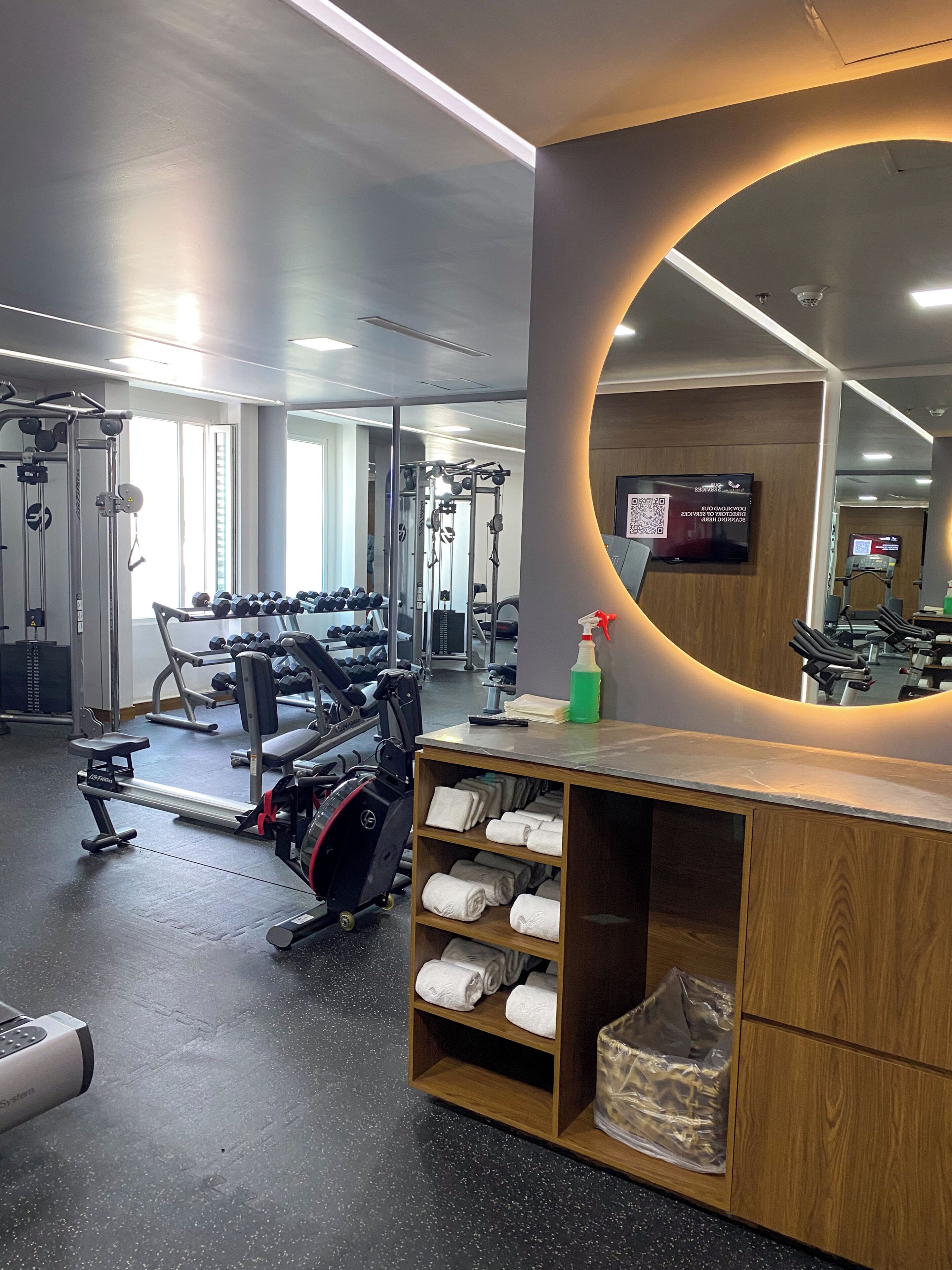A gym with exercise equipment, a mirror, and a towel rack.