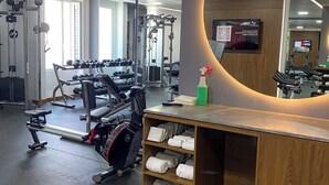 A gym with exercise equipment, a mirror, and a towel rack.
