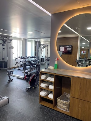A gym with exercise equipment, a mirror, and a towel rack.