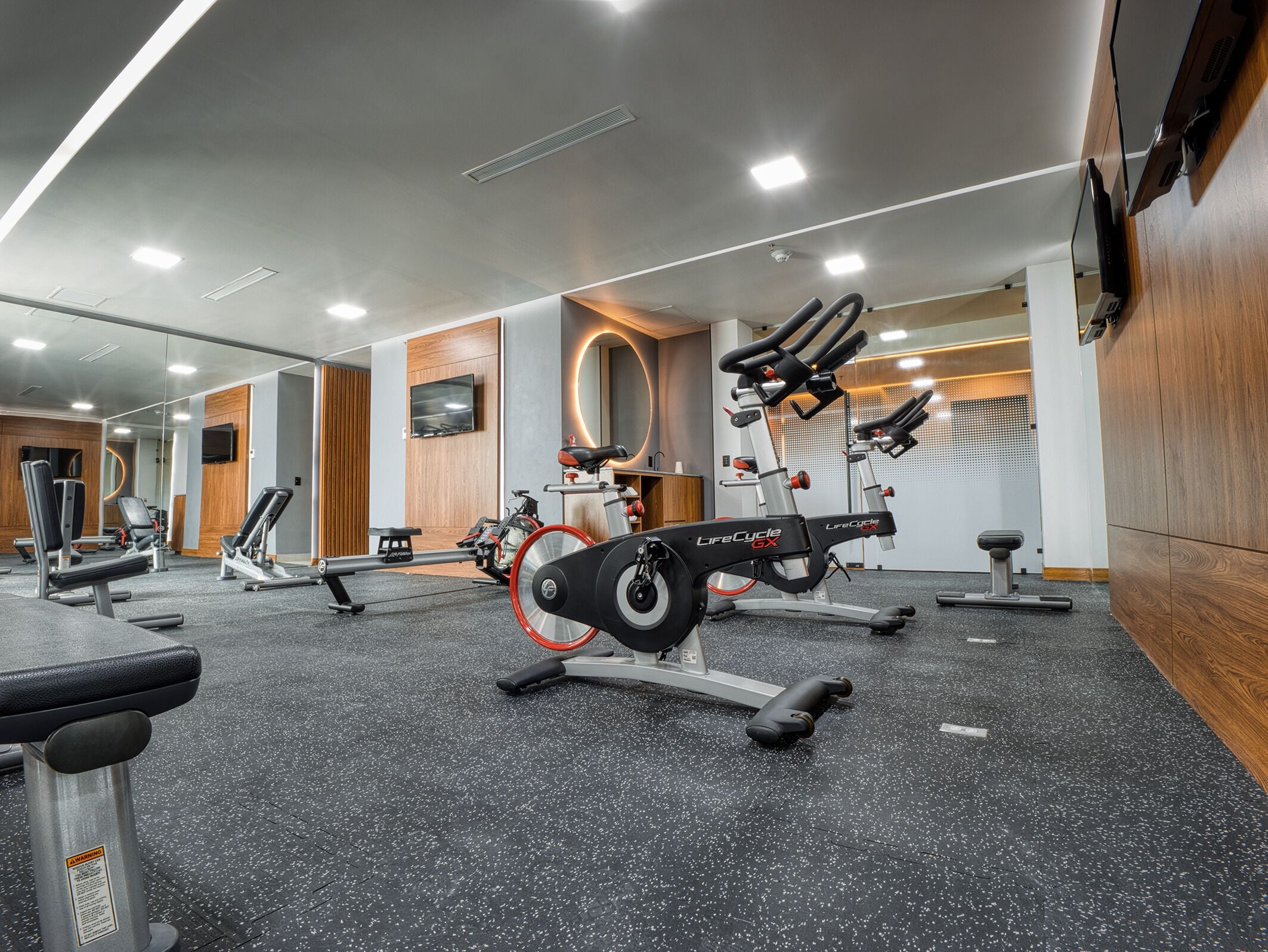 Un gimnasio con diversos equipos de ejercicio, incluyendo cintas de correr y bicicletas estáticas.