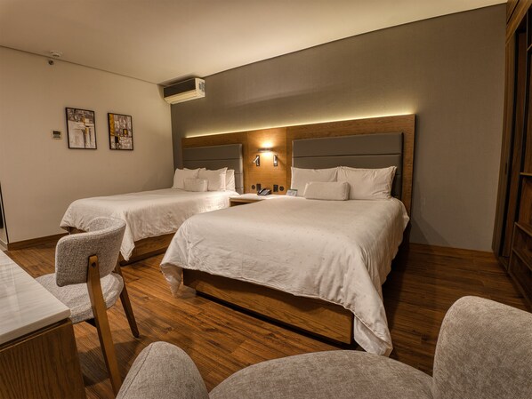 Ein Hotelzimmer mit zwei Betten, einem Schreibtisch und einem Stuhl.