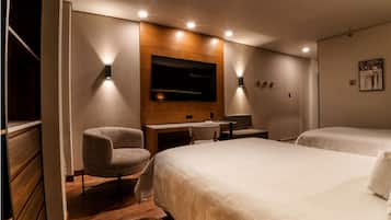 Habitación de hotel con una cama grande, un escritorio, una silla, un televisor montado en la pared y suelo de madera.