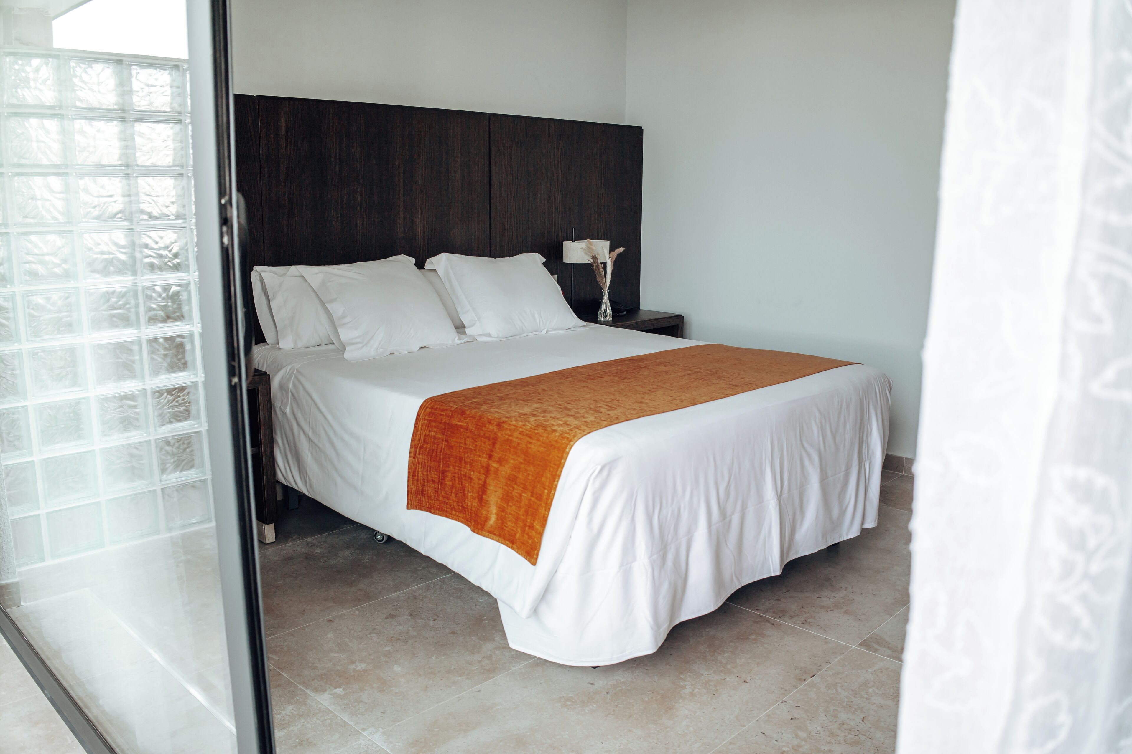 A bedroom with a bed, a nightstand, and a window.