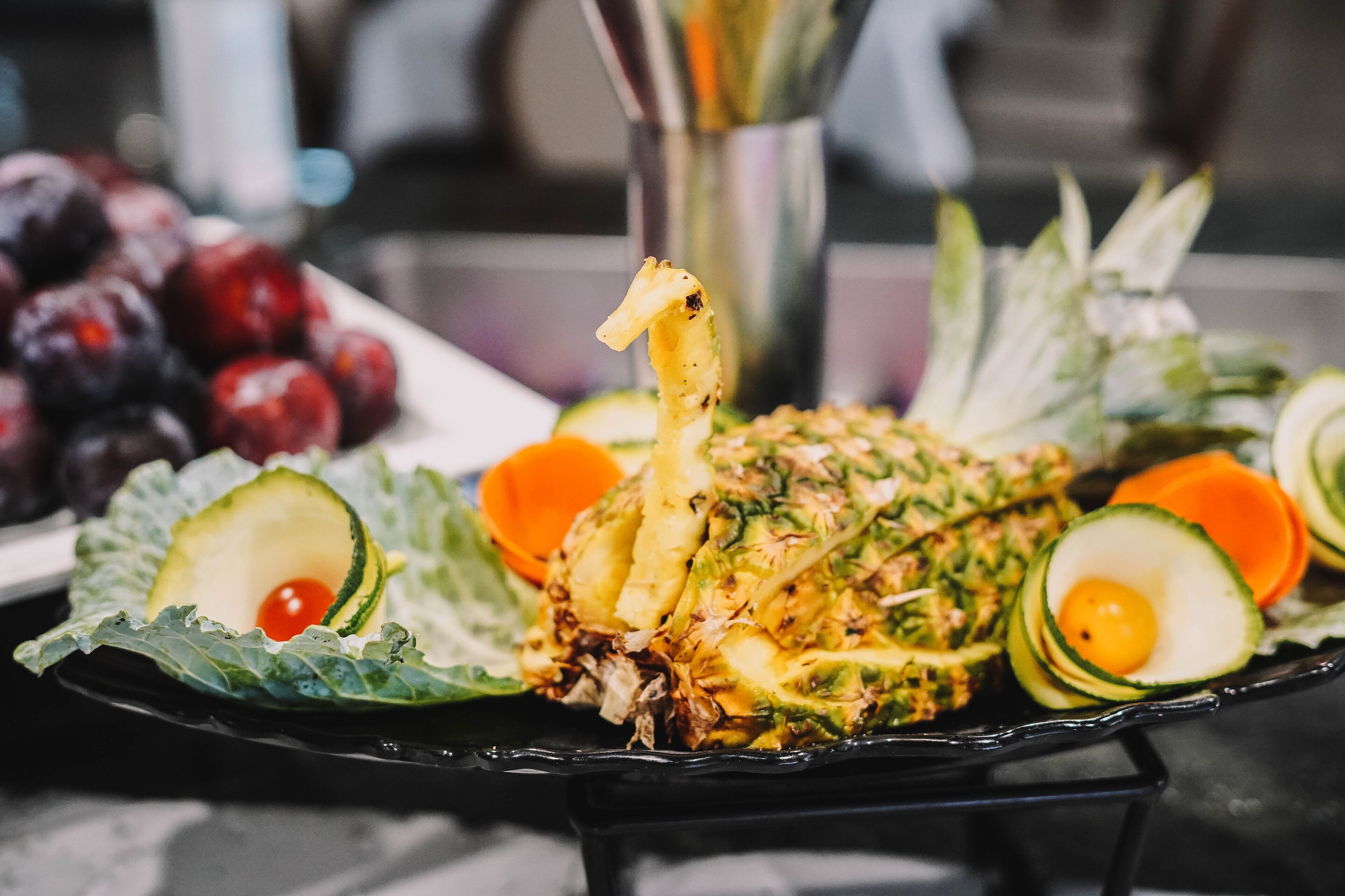 Ein Teller mit Speisen, darunter verschiedene Früchte und Gemüse wie Ananas, Avocado und Trauben.