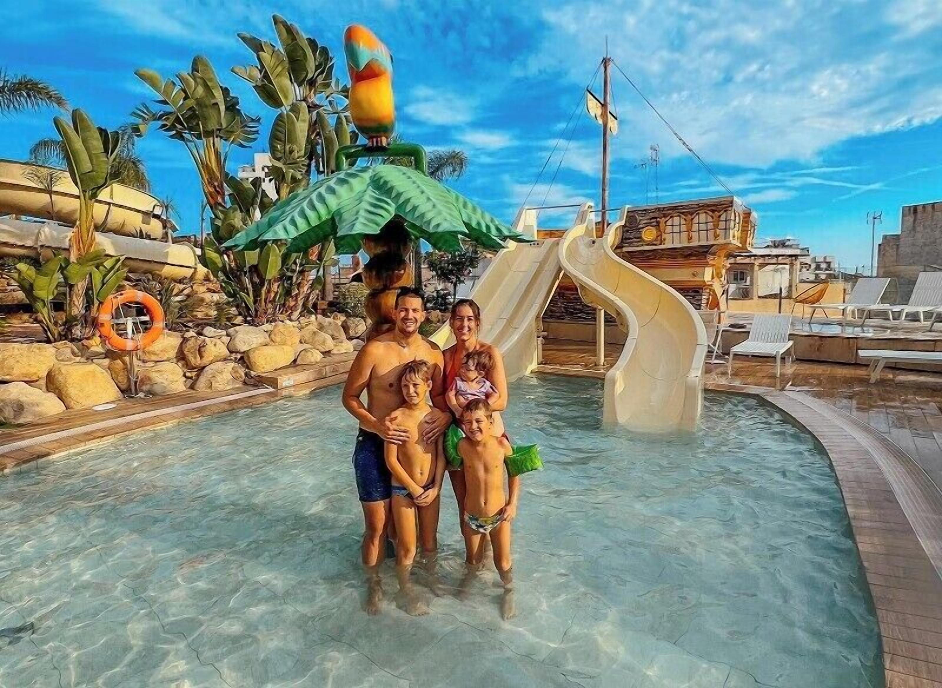 Ein Schwimmbecken mit Wasserrutsche, Palmen und einem Rettungsring.