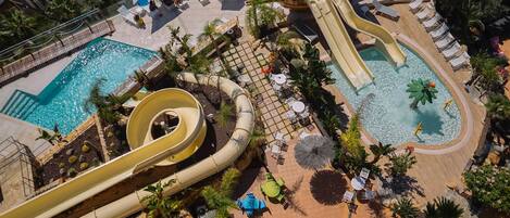 Un parc aquatique doté de nombreux toboggans et de plusieurs piscines, entouré d’espaces de détente et de palmiers.