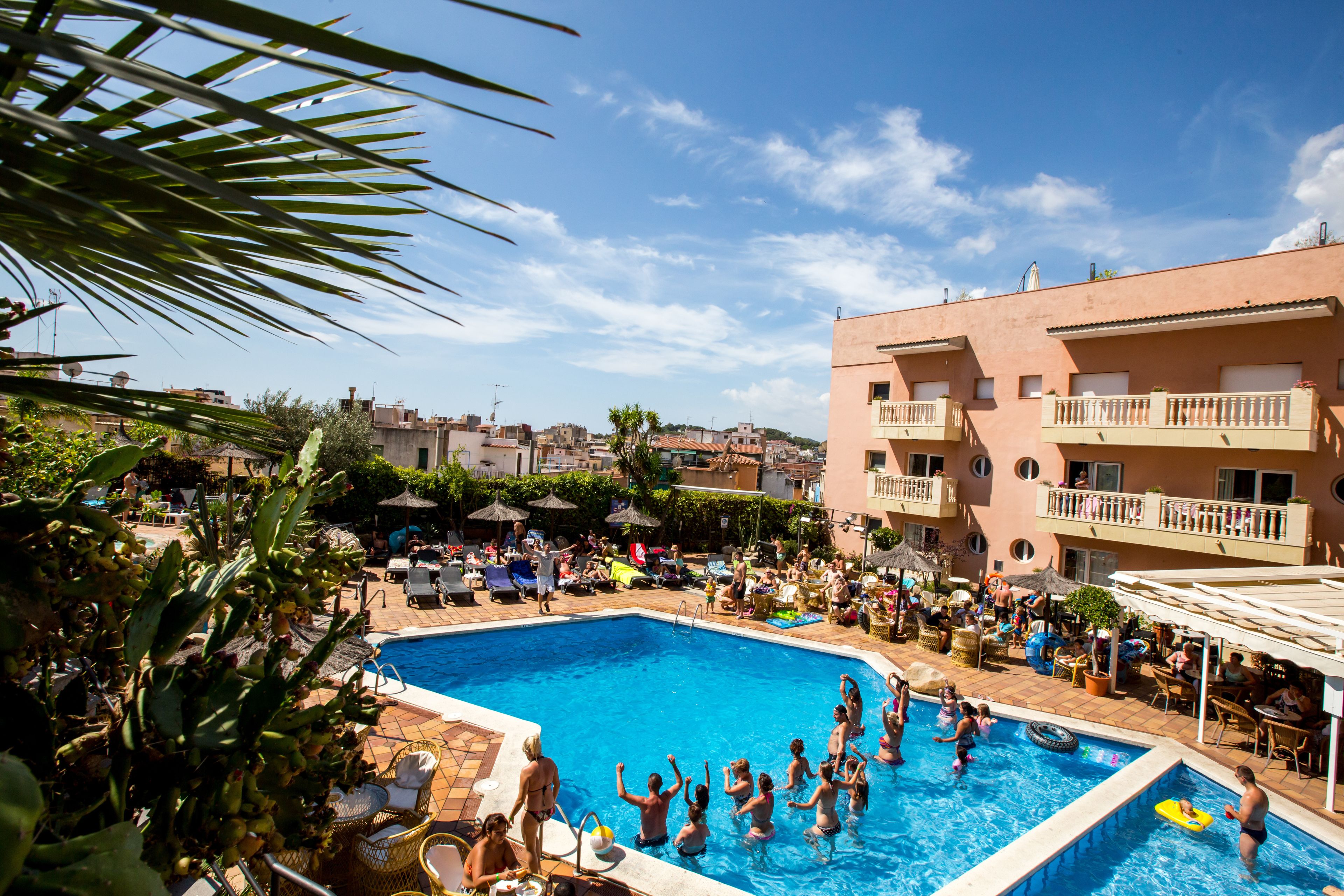 A swimming pool surrounded by lounge chairs and umbrellas, with a building in the background.