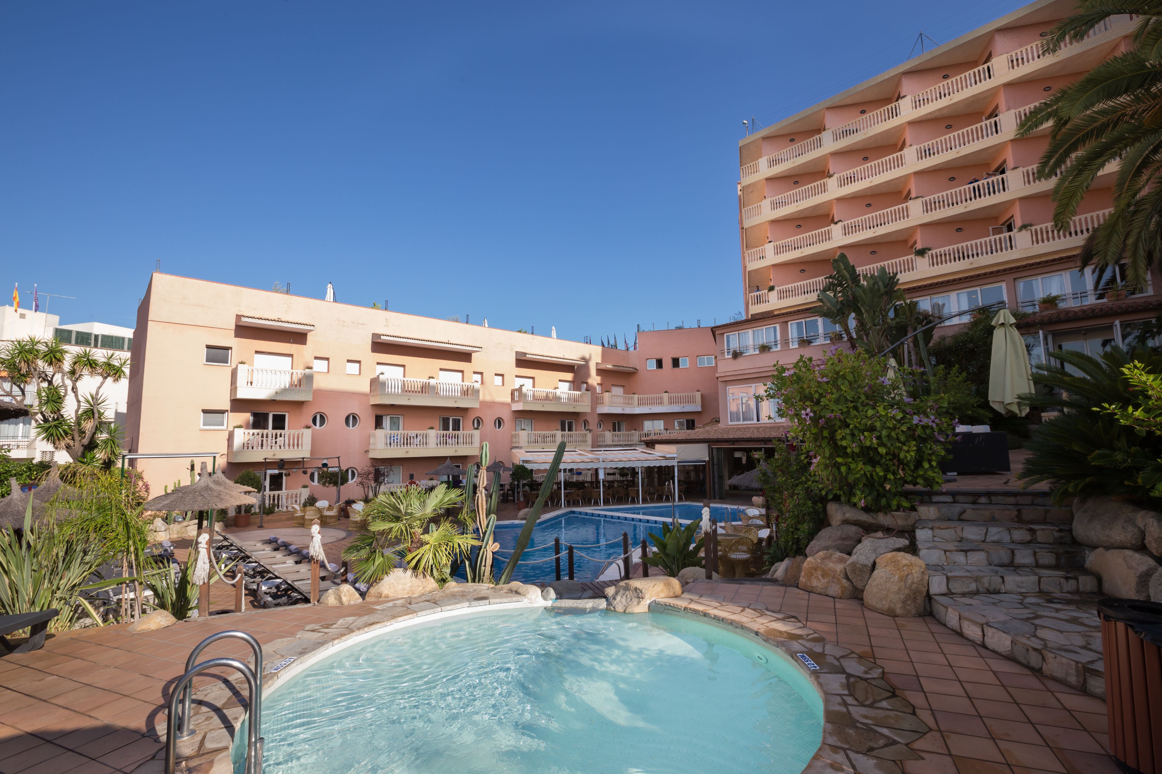 A hotel with a swimming pool, outdoor seating, and a garden area.