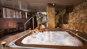 A spa area with a hot tub, stone walls, and a staircase leading to an upper level. - Alba Seleqtta (Lloret de Mar)