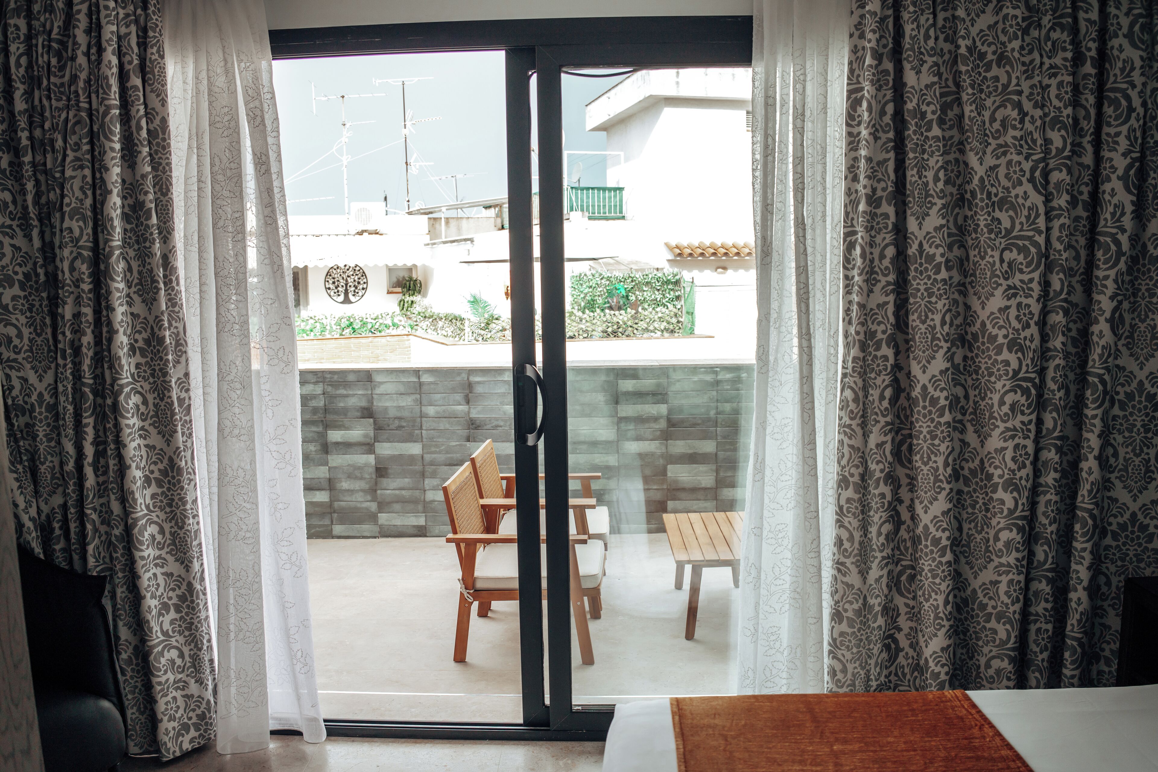 A hotel room with a sliding glass door leading to an outdoor seating area with a table and chairs.