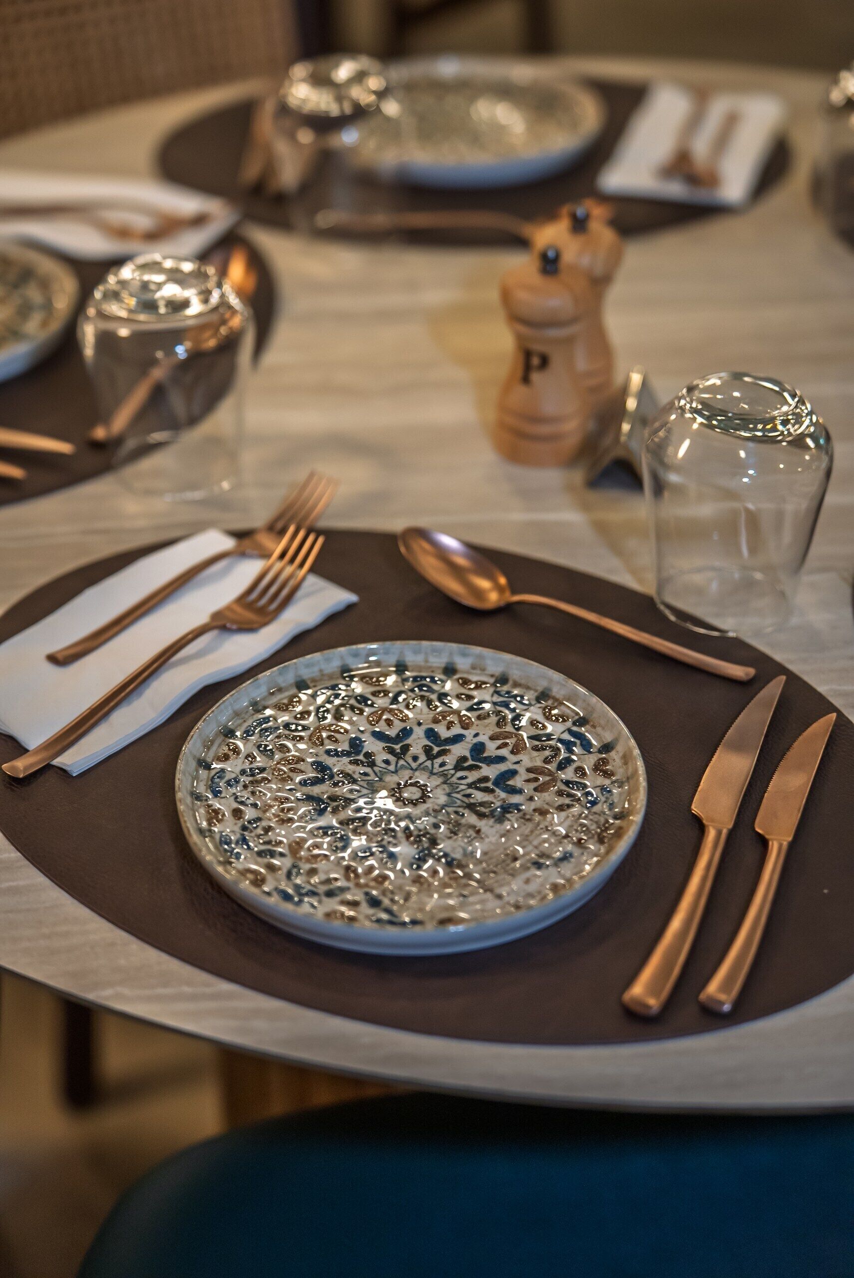 A dining table set with a plate, cutlery, and a salt and pepper shaker.