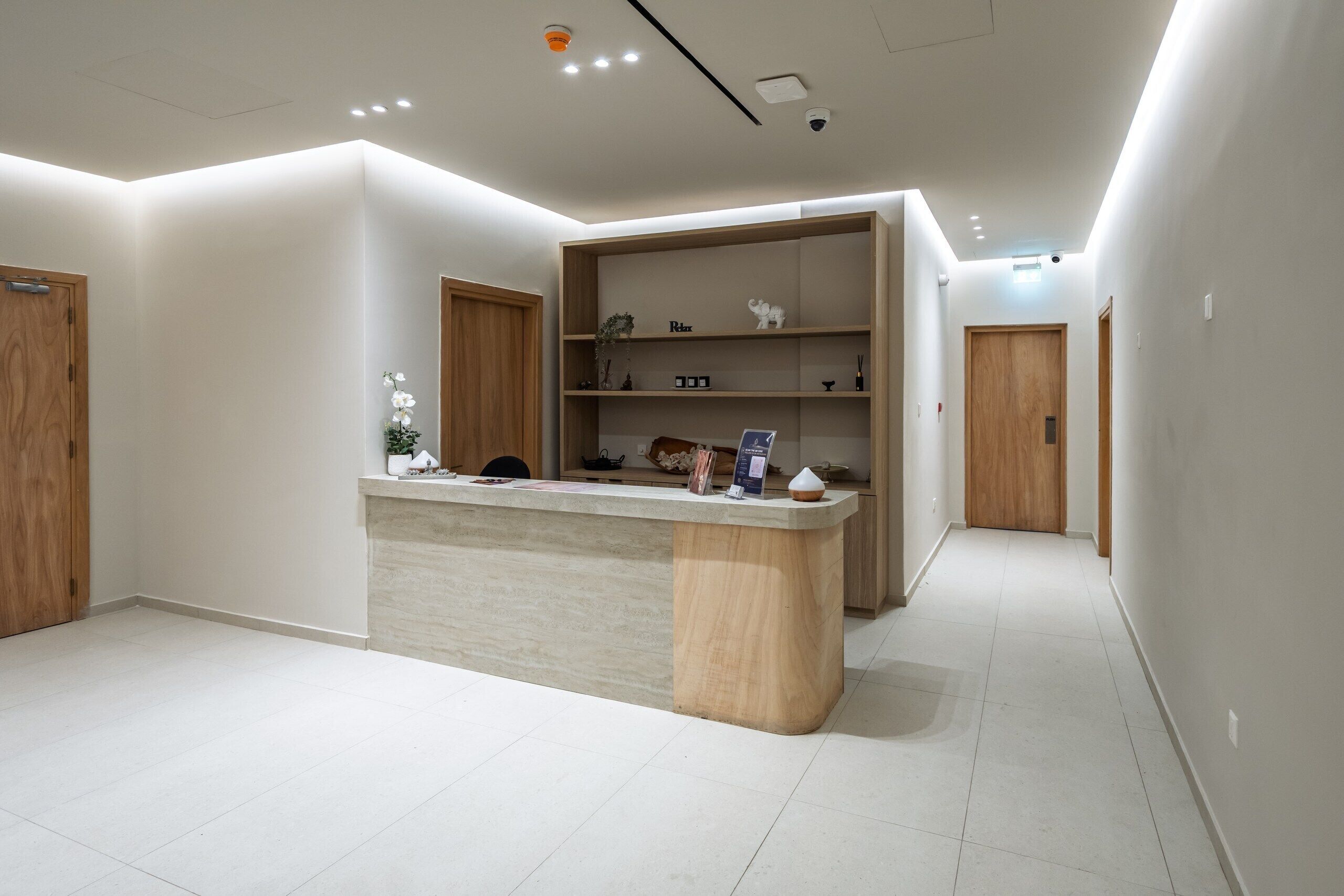 A modern interior with a reception desk, wooden doors, and a hallway.