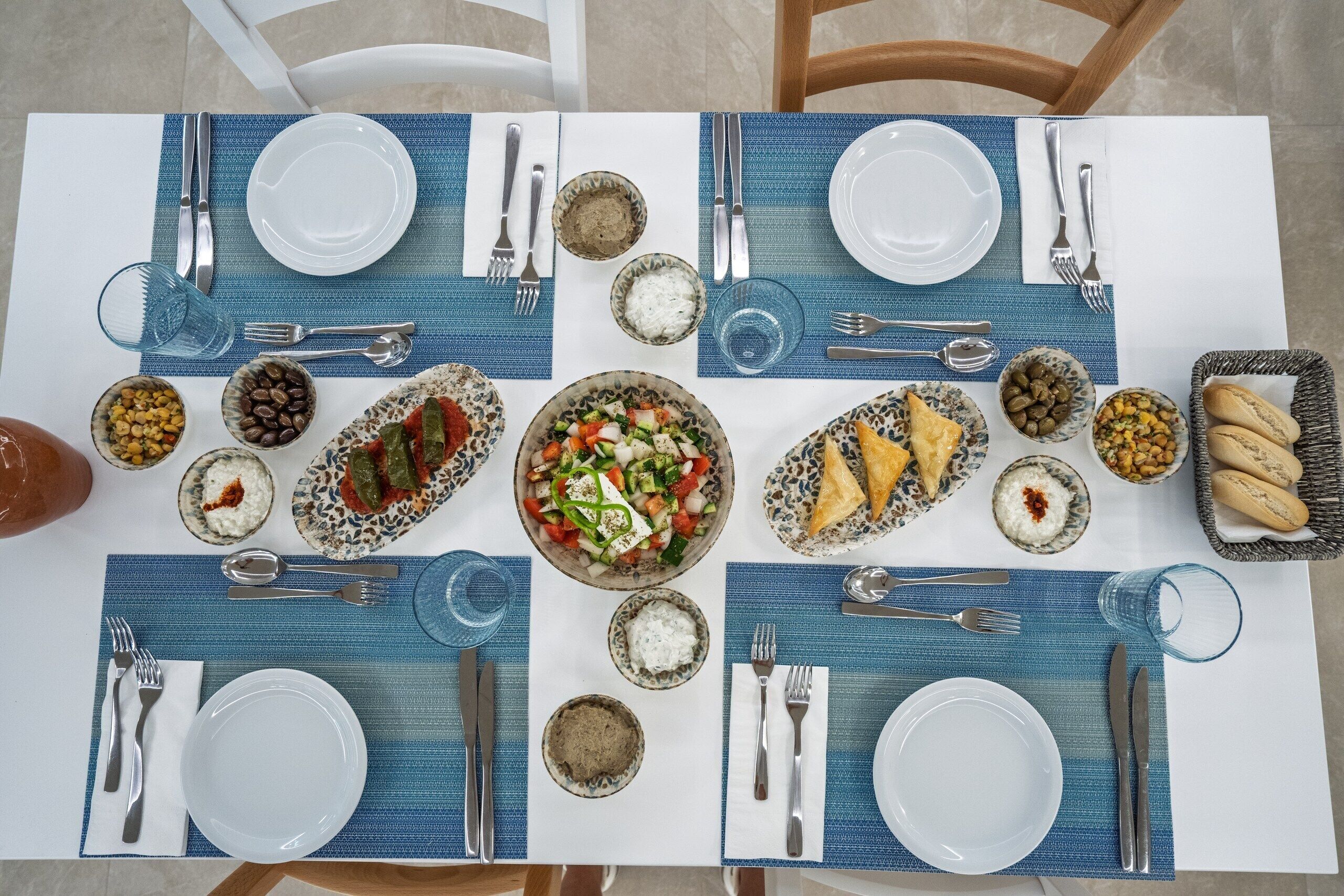 Una mesa servida para una comida con platos, cubiertos y diferentes fuentes.