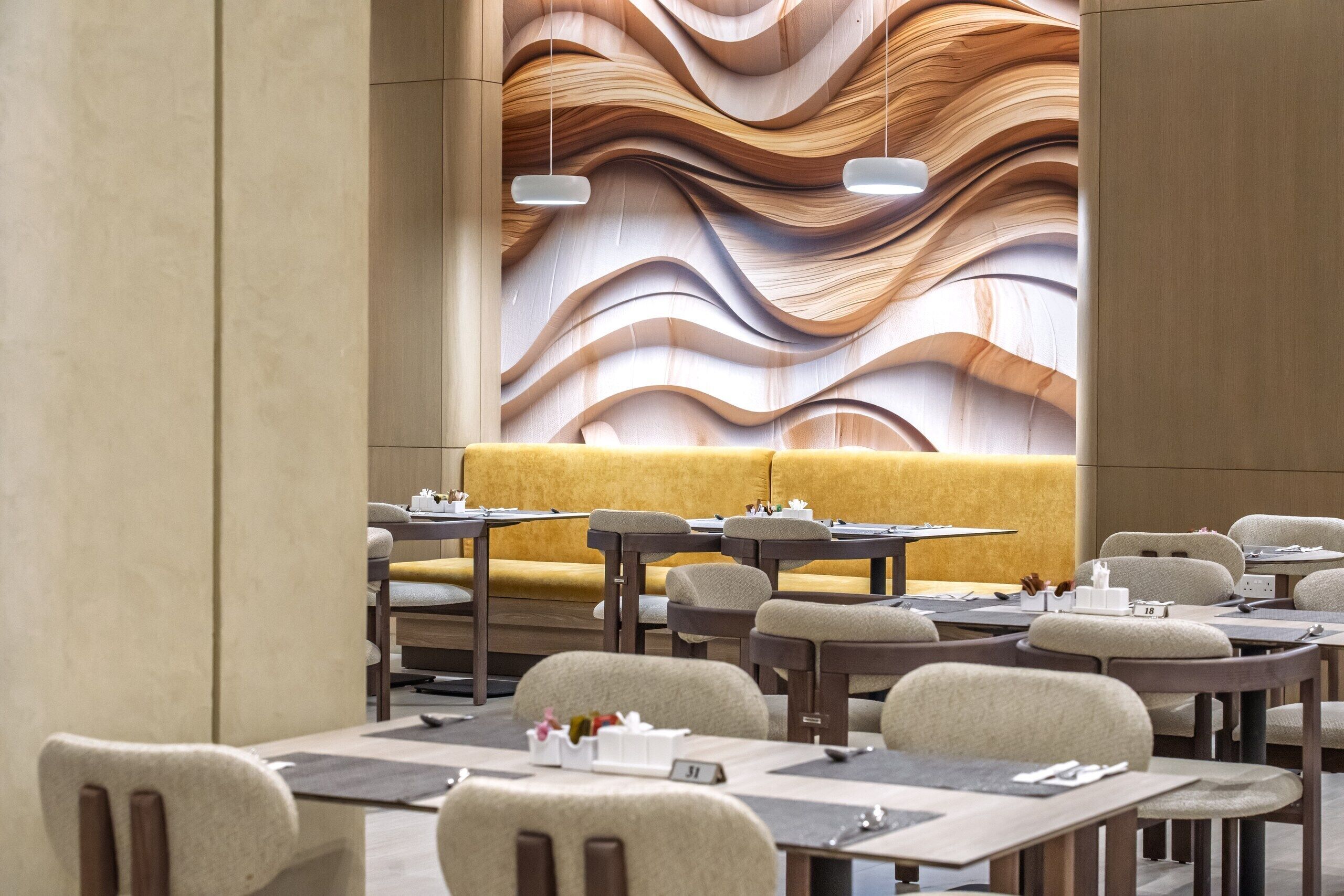 A modern restaurant interior with a central yellow sofa, multiple tables, and chairs.
