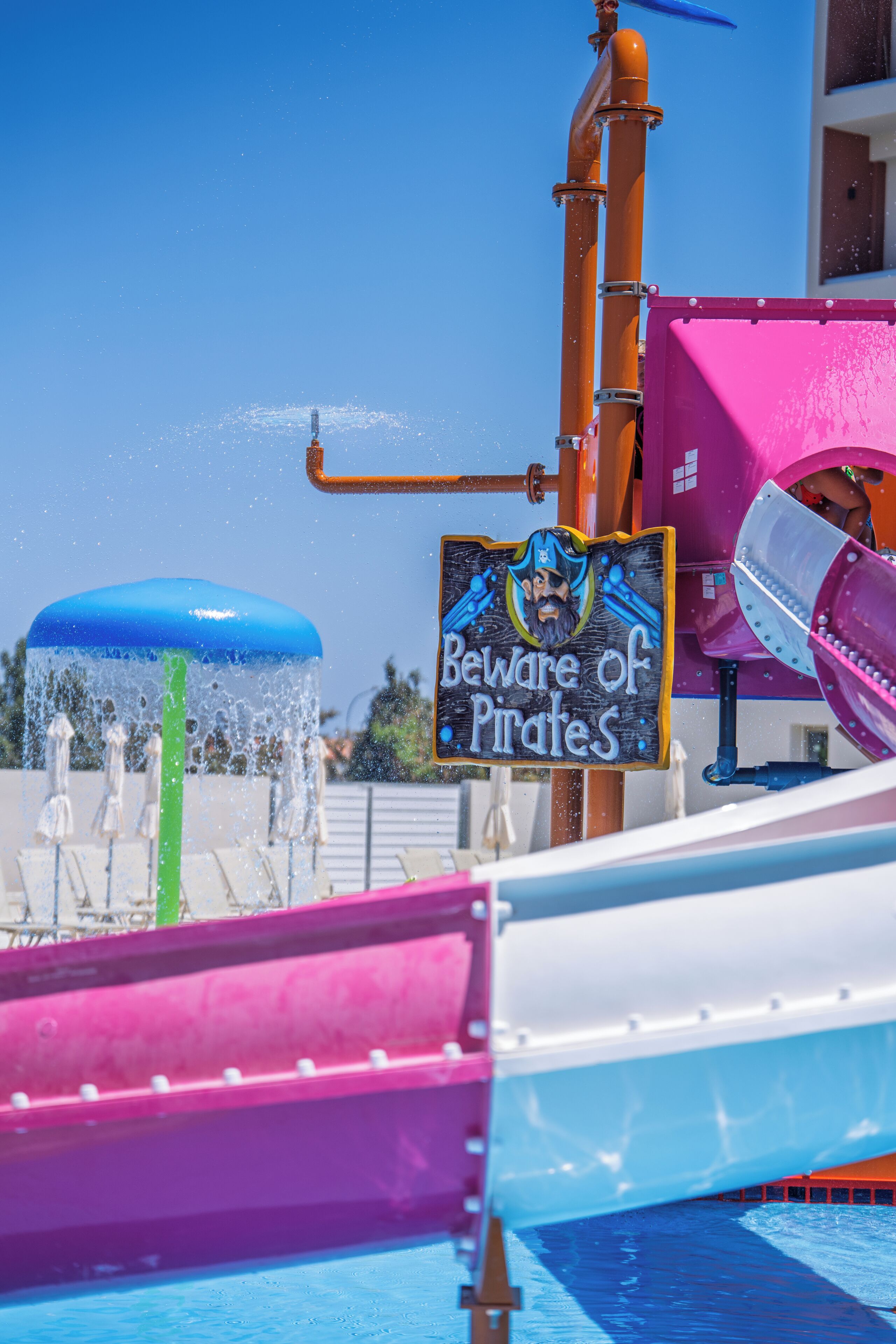A water park with a sign warning of pirates, water slides, and a blue water feature.