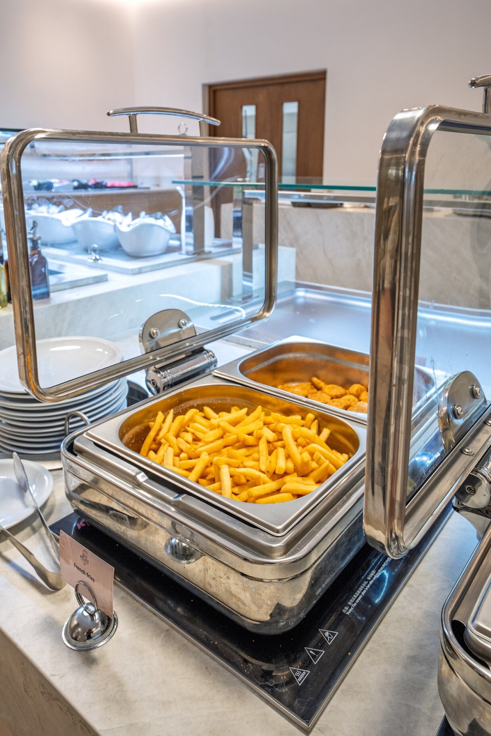 A buffet setup with a French fries container and a glass display case.
