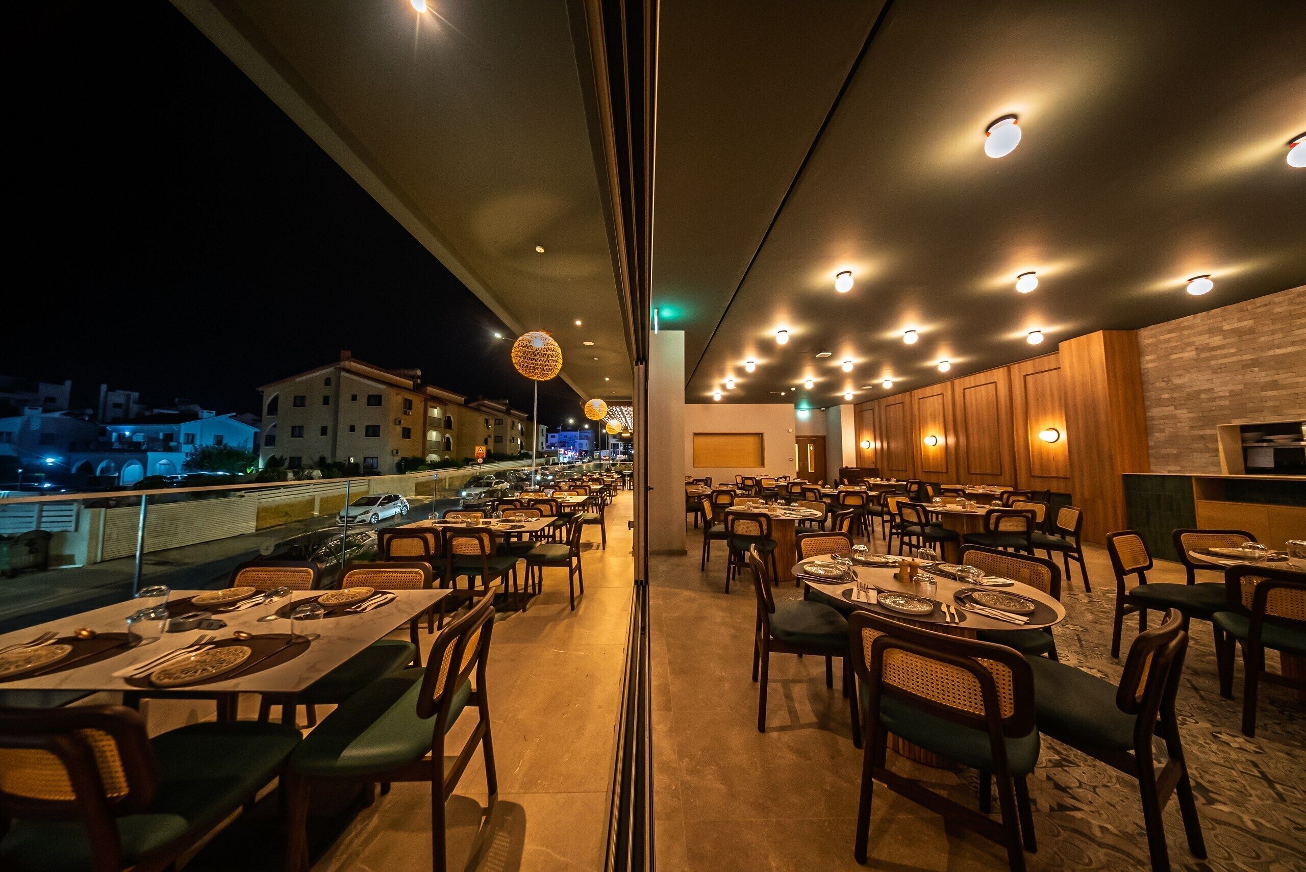 An outdoor dining area with tables and chairs, a view of the cityscape, and a building with a brick facade.