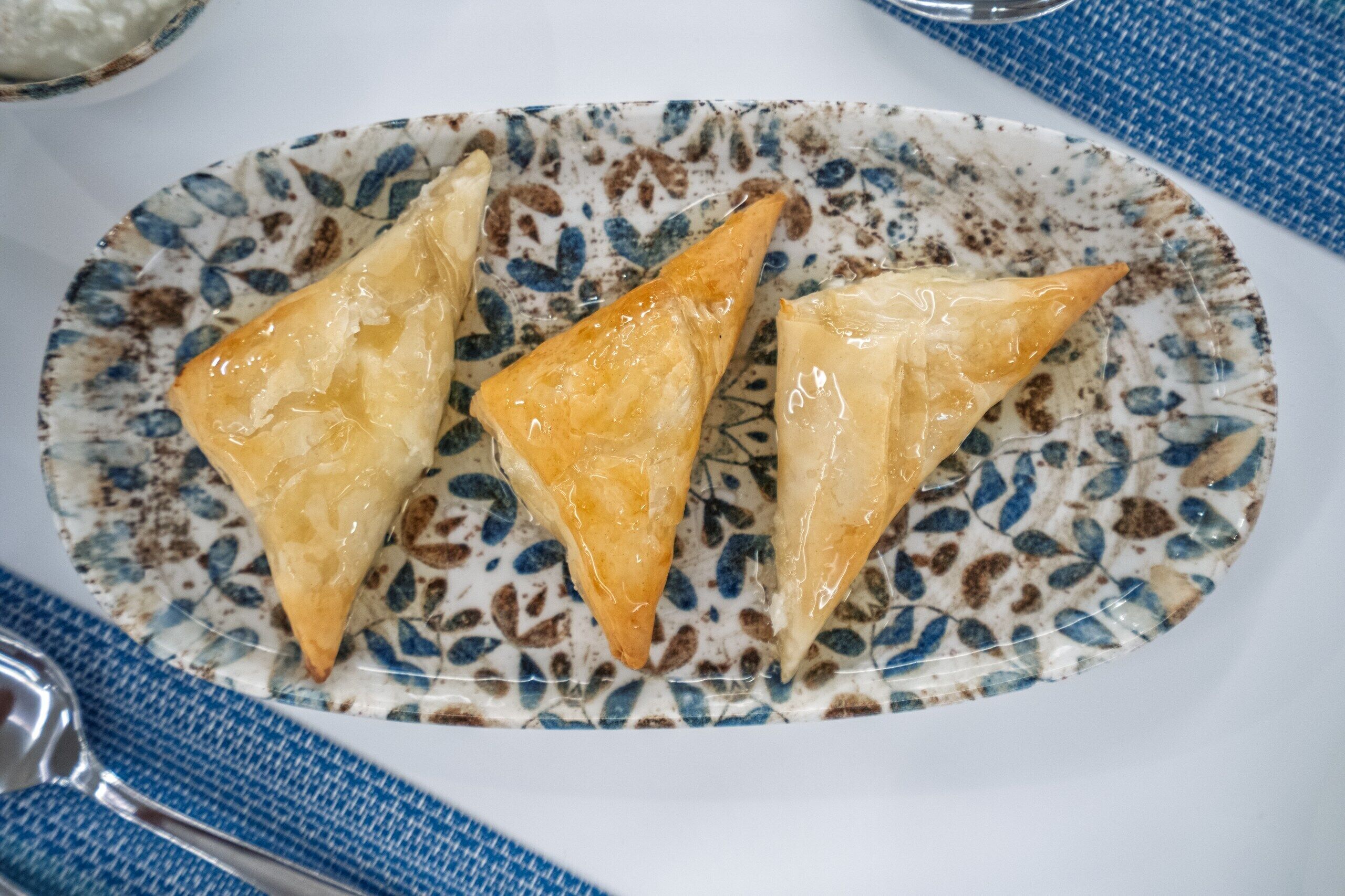 A plate with three triangular pastries on a patterned ceramic plate.