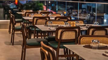 Un espacio exterior con mesas y sillas para comer, farolas y vistas de la ciudad de noche.