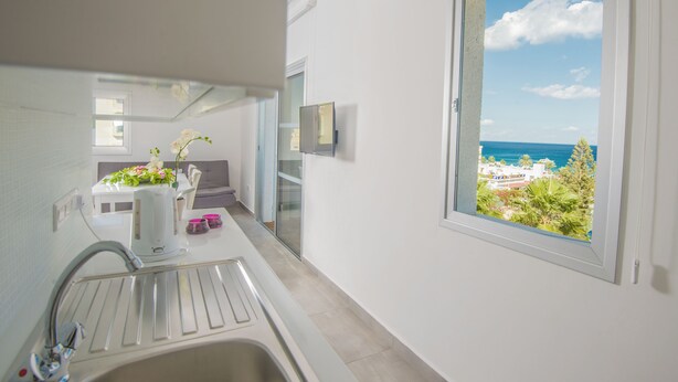 Un baño moderno con lavamanos, espejo y ventana con vistas al mar y al verdor.