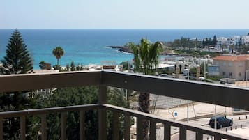 Un balcón con vista al mar, edificios y un estacionamiento.