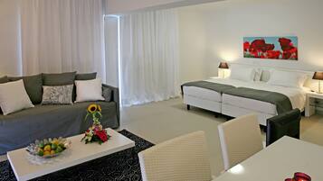 Ein Hotelzimmer mit Bett, Sofa, Esstisch und Couchtisch.