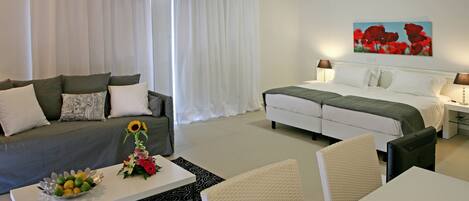 Una habitación de hotel con cama, sofá, mesa de comedor y una mesa de centro.