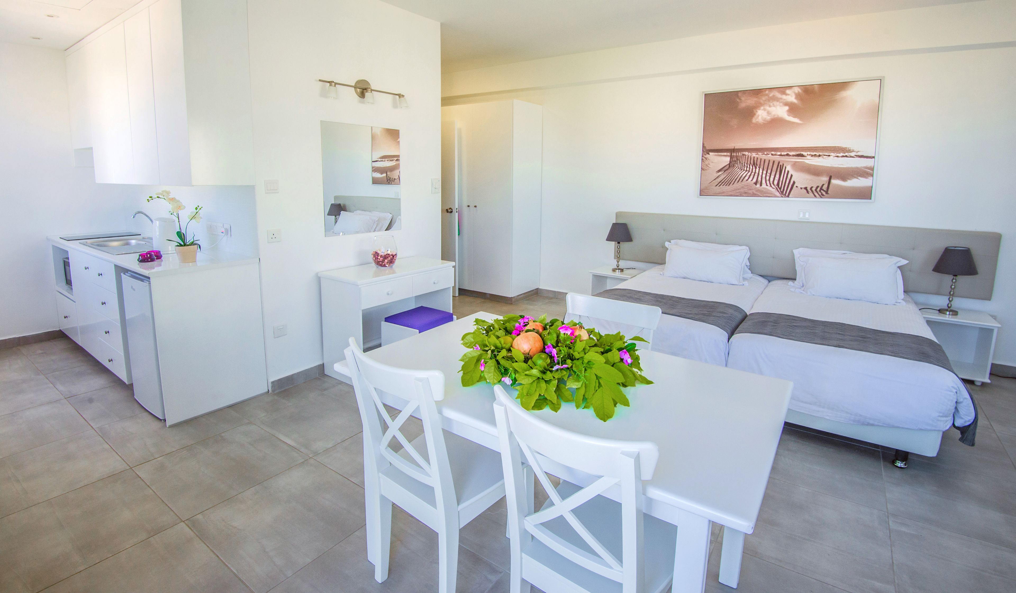 Una habitación de hotel moderna con cama, escritorio, silla, kitchenette y baño.