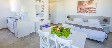 Una habitación de hotel moderna con cama, escritorio, silla, kitchenette y baño.