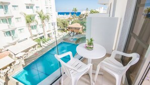 Un balcón con piscina, sillas blancas y una mesa con una planta.
