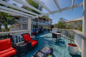 Eine überdachte Terrasse im Freien mit Korbmöbeln, einem Tisch und einem Blumentopf.