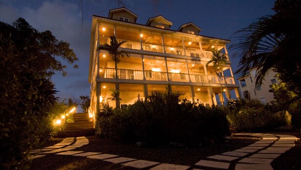 Un hotel de varios pisos con balcones, una entrada bien iluminada y un camino que conduce al edificio.