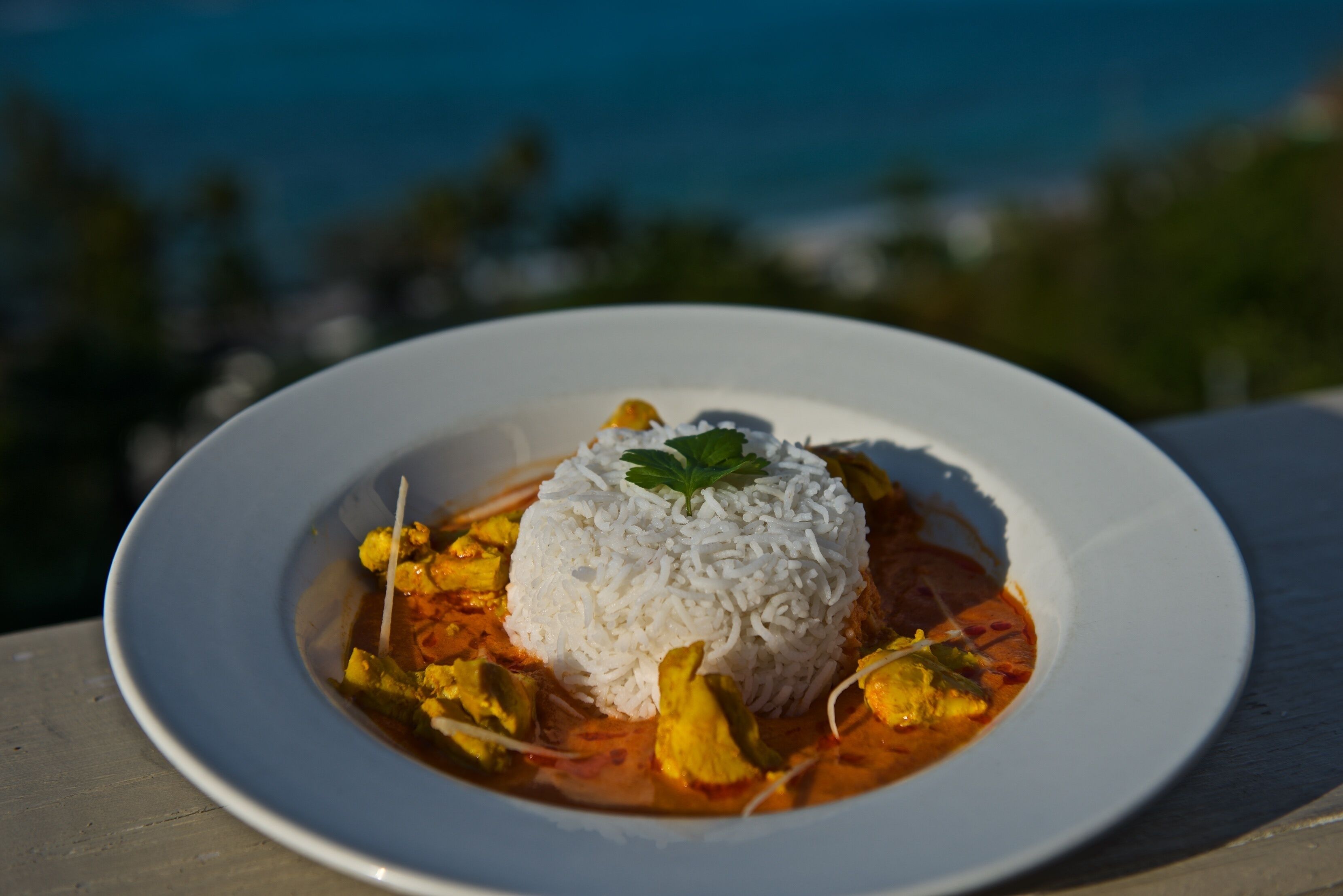 A plate of white rice topped with a garnish, served with a curry-like dish.