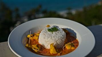 A plate of white rice topped with a garnish, served with a curry-like dish.