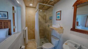 A bathroom with a shower, toilet, sink, and wooden ceiling.
