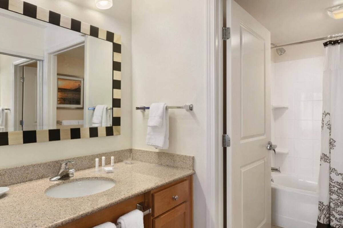 A bathroom with a sink, mirror, towel rack, and shower curtain.
