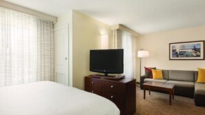 A hotel room with a large bed, a flat-screen TV on a wooden dresser, a sofa with cushions, and a framed picture on the wall. - Residence Inn by Marriott Newport/Middletown (Middletown)