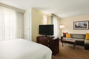 A hotel room with a large bed, a flat-screen TV on a wooden dresser, a sofa with cushions, and a framed picture on the wall. - Residence Inn by Marriott Newport/Middletown (Middletown)