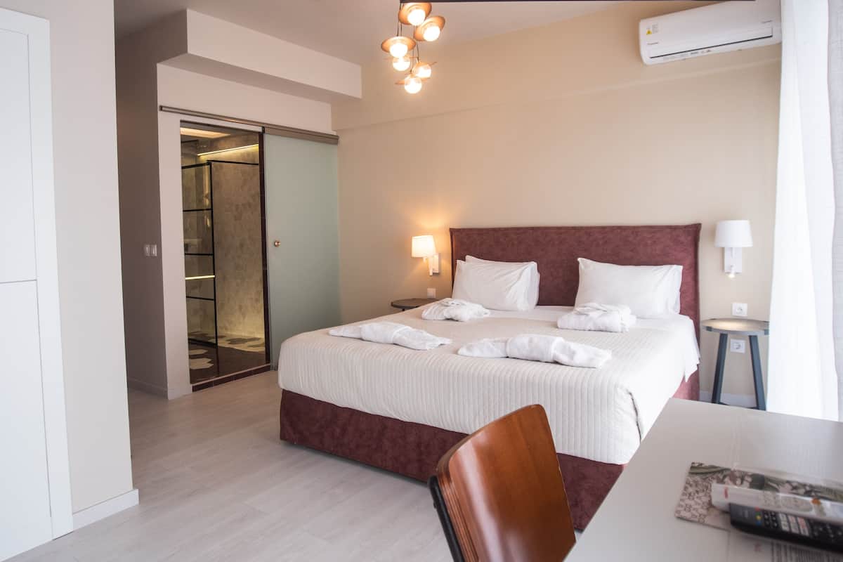 A hotel room with a bed, bedside table, chair, and a wardrobe.