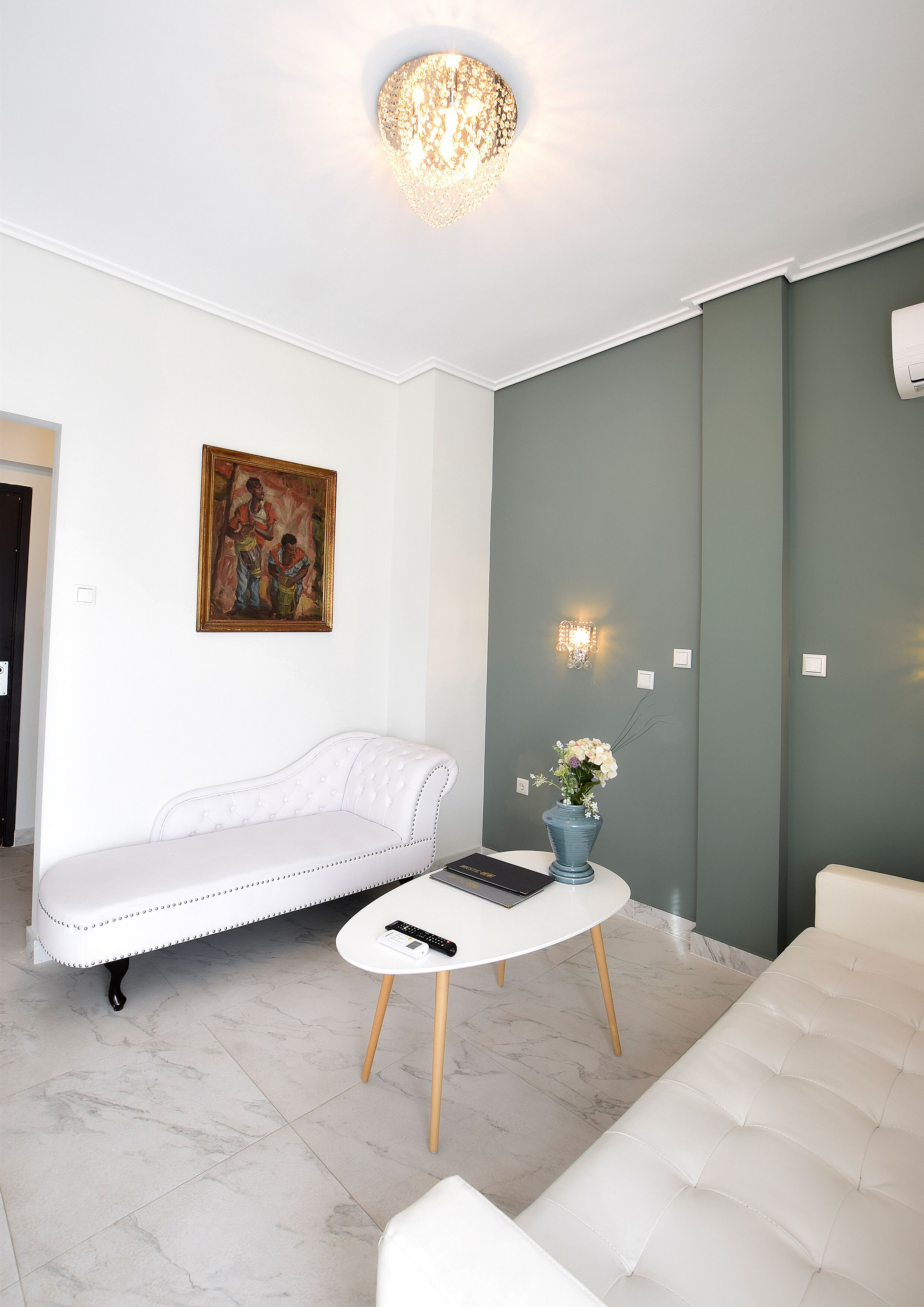 A modern living room with a white sofa, a white armchair, a round coffee table, and a painting on the wall.