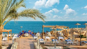 A beachside restaurant with outdoor seating, a view of the sea, and a wooden pergola structure. - Dreams Beach Sharm el Sheikh (Sharm El Sheikh)