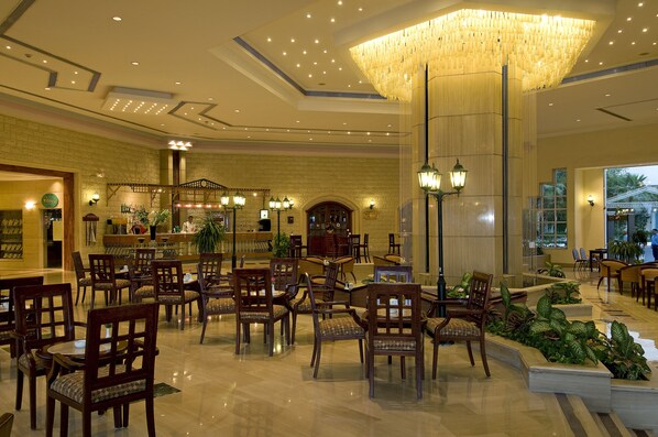 A spacious lobby with multiple seating areas, a reception desk, and a large chandelier.