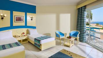 A hotel room with two beds, a balcony with a view, and a dining area.