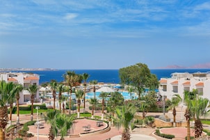 A resort with a pool area, palm trees, and a view of the sea.