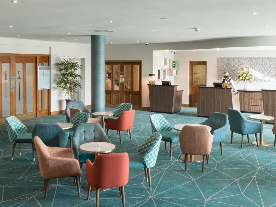 Vestíbulo con mostrador de recepción, zona de estar con sillones estampados y un pilar grande.