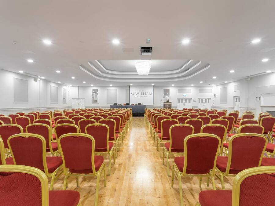 Una sala de conferències amb files de cadires vermelles i un escenari al capdamunt.