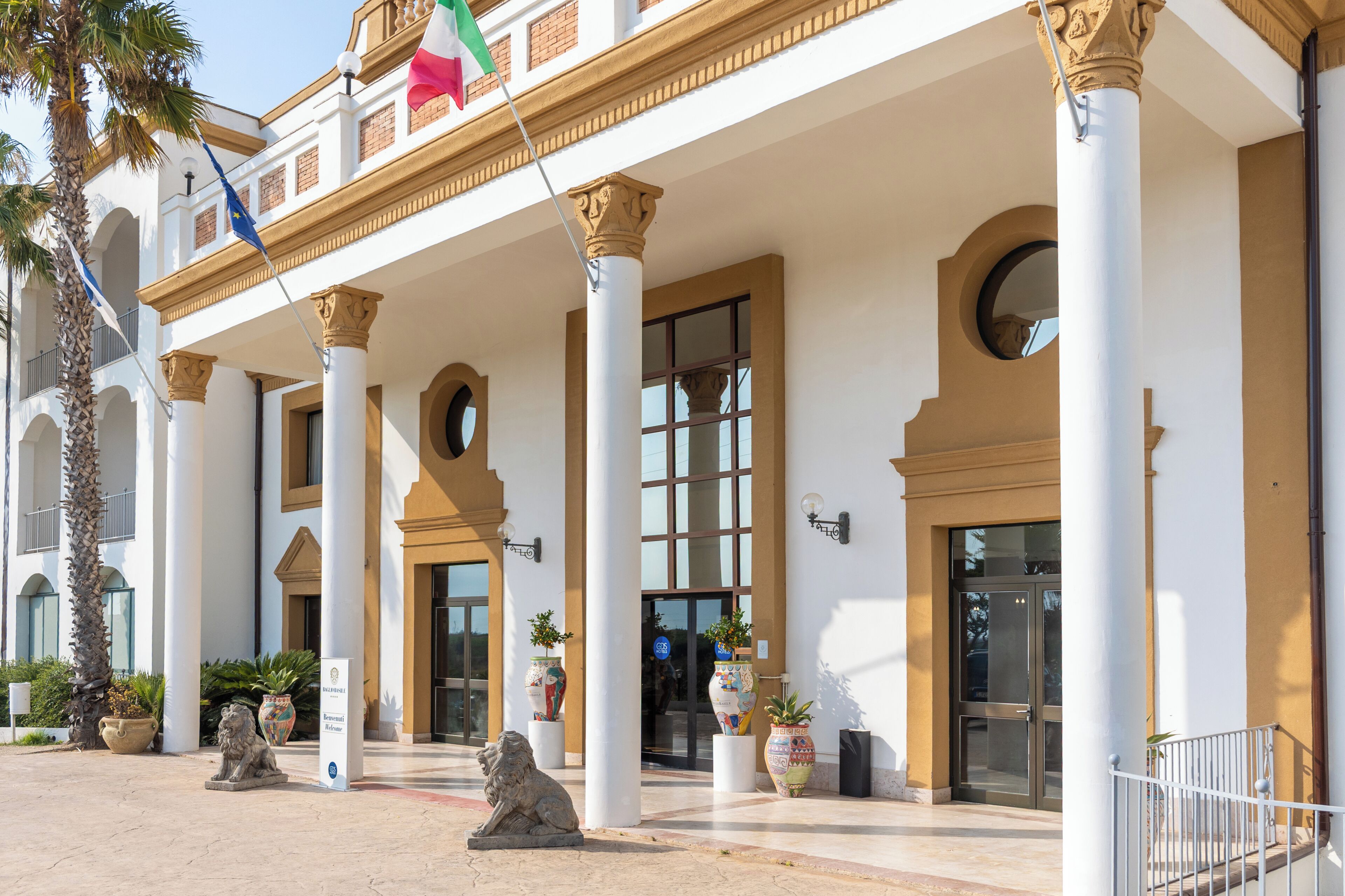 A hotel entrance with a white facade, columns, and a flag.